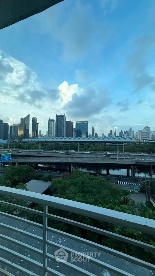 Stunning city skyline view from a balcony overlooking lush greenery and urban landscape.