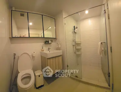 Modern bathroom with glass shower and sleek vanity in contemporary home.