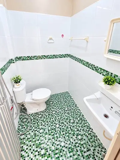 Charming bathroom with green mosaic tiles and modern fixtures, perfect for a refreshing start to your day.