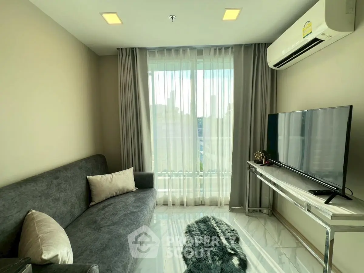 Modern living room with sleek furniture and large window offering natural light.