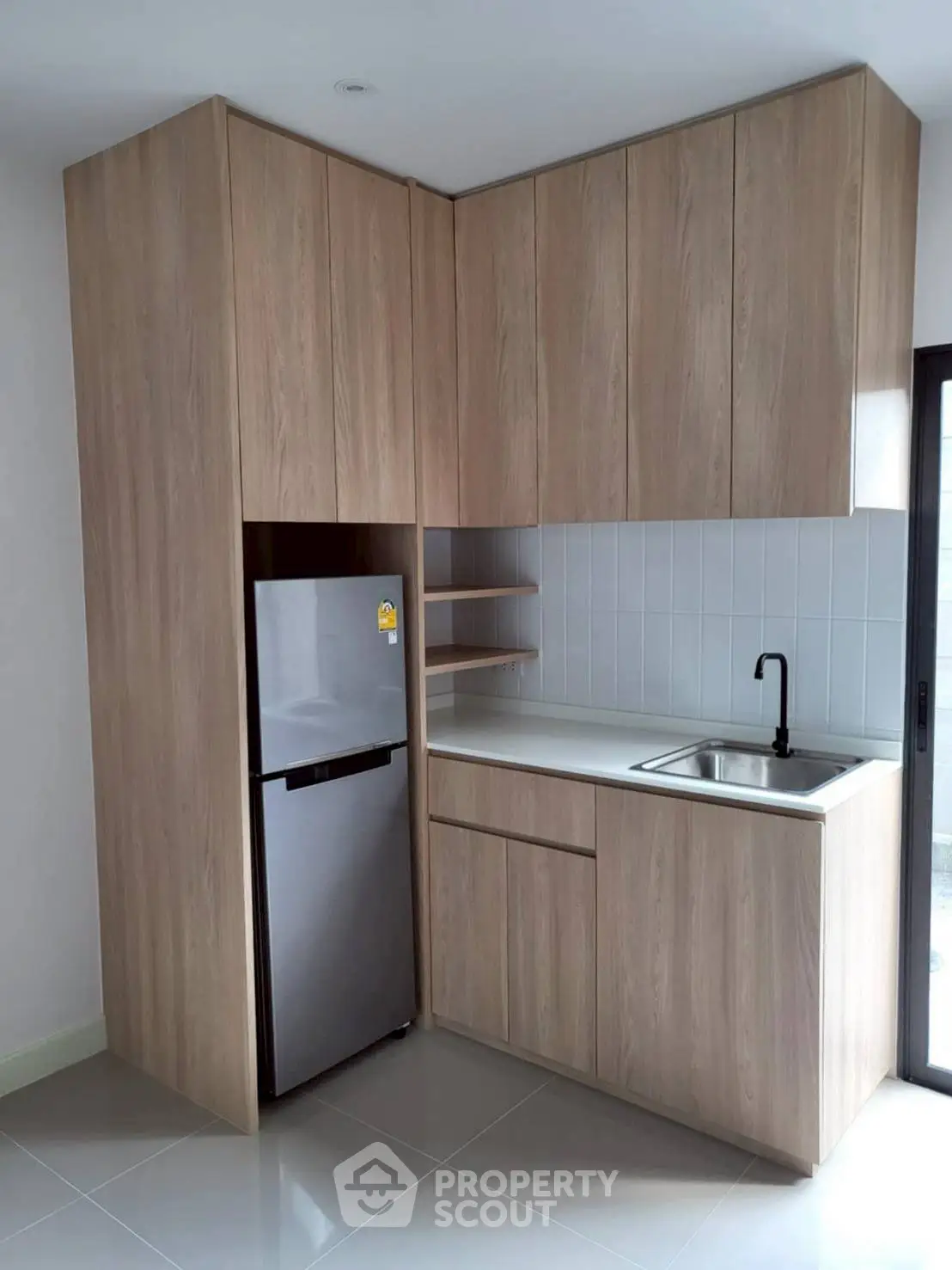 Modern kitchen with sleek cabinetry and stainless steel fridge in compact layout.