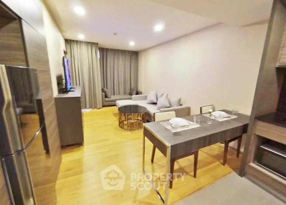 Modern living room with stylish furniture and open layout, featuring a cozy dining area and sleek wooden flooring.