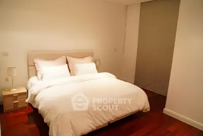 Cozy bedroom with elegant wooden flooring and soft lighting, perfect for relaxation.