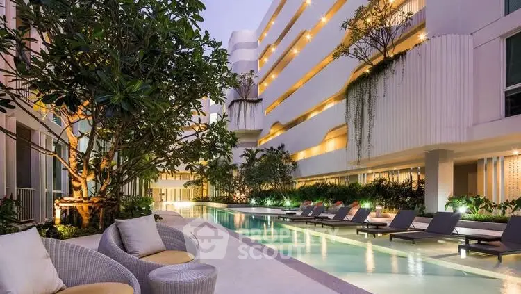 Luxurious modern apartment complex with stunning poolside lounge area and lush greenery.