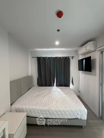 Modern bedroom with cozy bed, wall-mounted TV, and air conditioning in a stylish apartment.