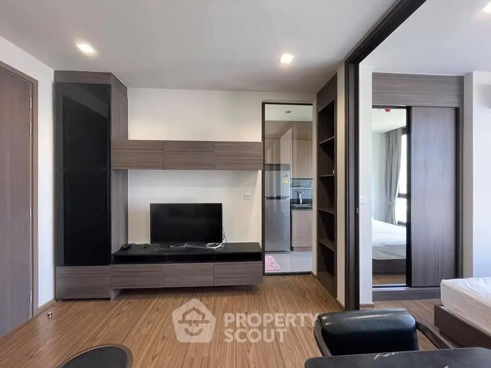 Modern living room with sleek wooden flooring and stylish built-in entertainment unit.