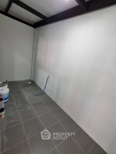 Spacious unfinished room with tiled floor and plumbing, ideal for customization.