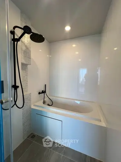 Modern bathroom with sleek bathtub and stylish black shower fixtures.