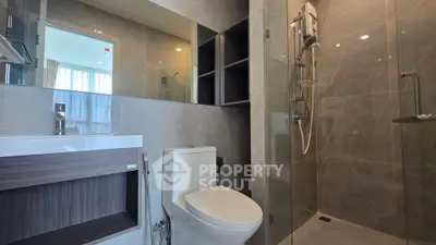 Modern bathroom with glass shower and sleek fixtures in contemporary apartment.