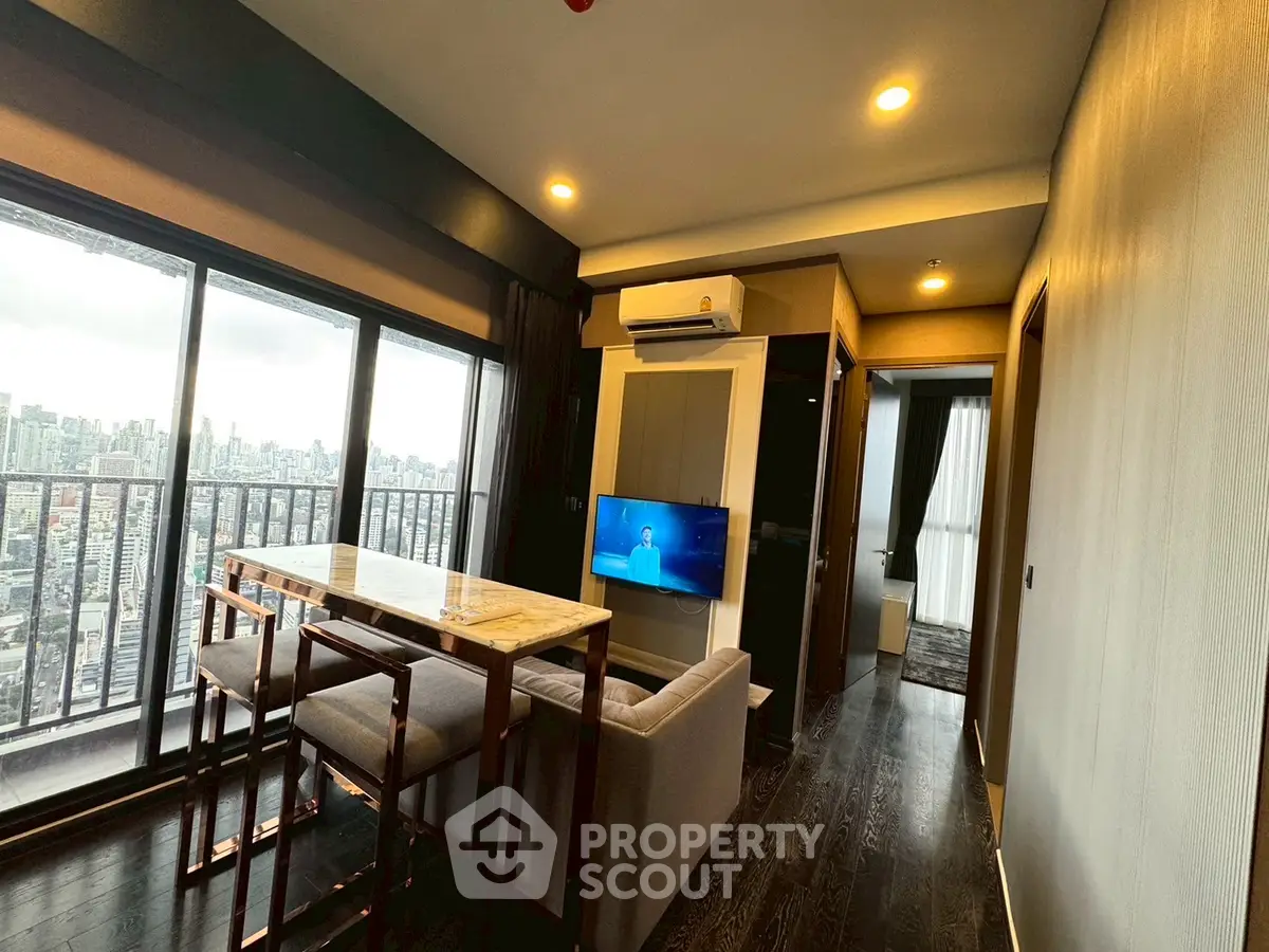 Modern living room with city view, featuring sleek furniture and large windows.