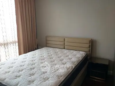 Cozy bedroom with plush mattress and elegant curtains, perfect for restful nights.