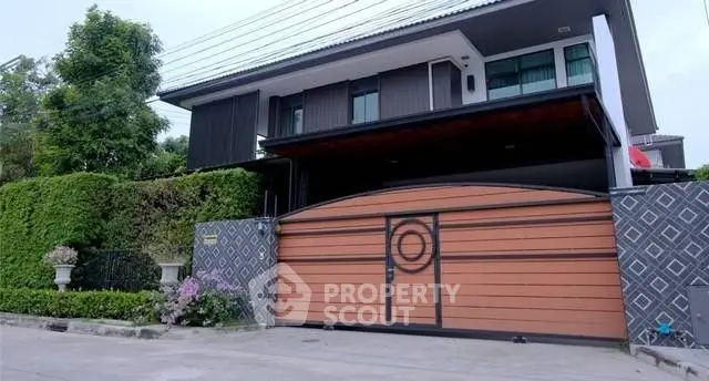 Modern two-story house with stylish gate and lush greenery