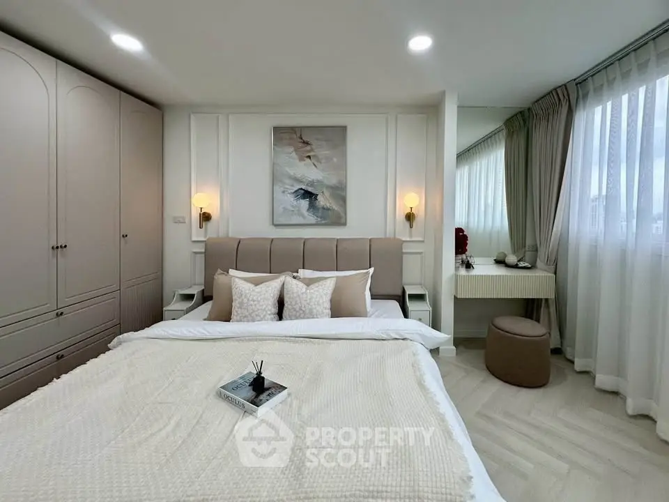 Elegant bedroom with cozy bedding, stylish decor, and ample natural light from large windows.
