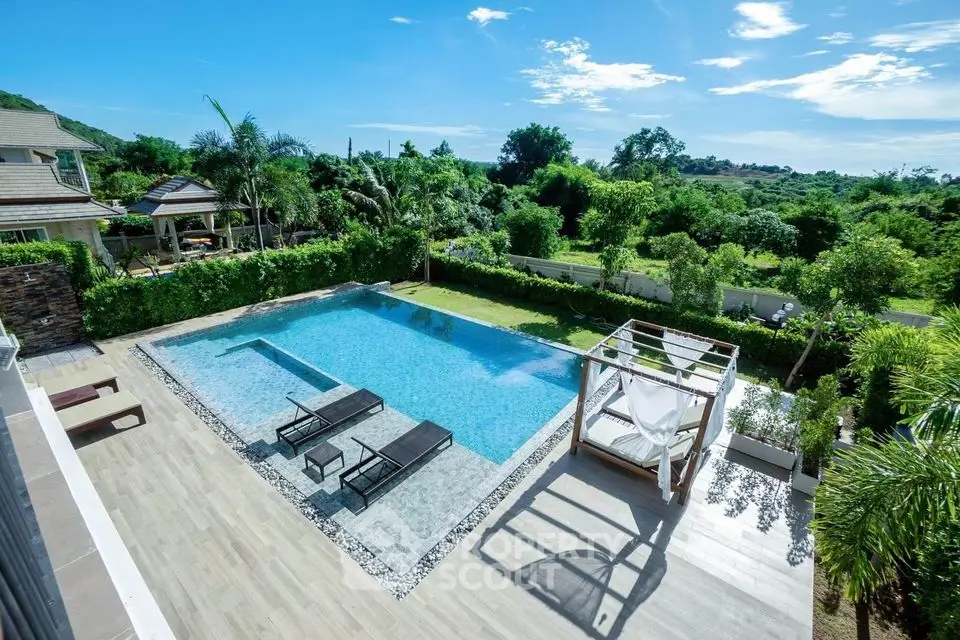 Luxurious outdoor pool with sun loungers and lush greenery in a serene setting