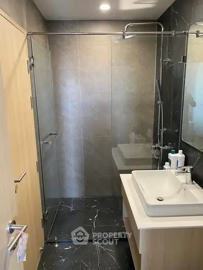Modern bathroom with glass shower enclosure and sleek vanity in a contemporary home.