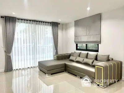 Modern living room with elegant gray sectional sofa and large window with curtains