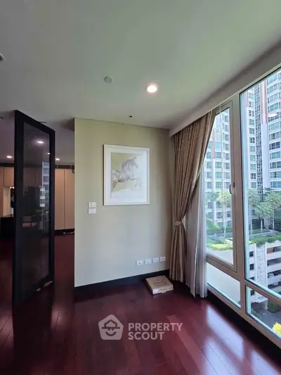 Spacious living room with large windows offering a stunning view of modern high-rise buildings.
