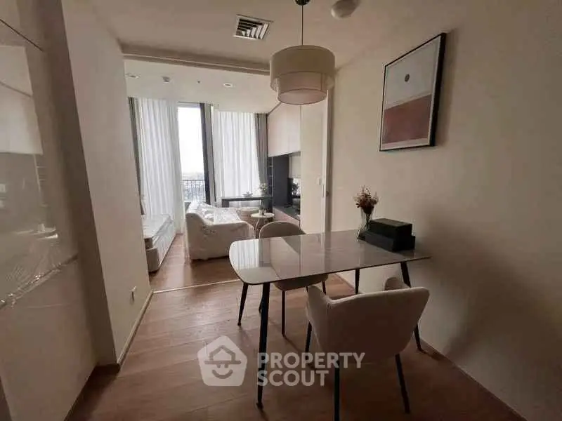 Modern apartment interior with dining area and cozy living space, featuring large windows and stylish decor.