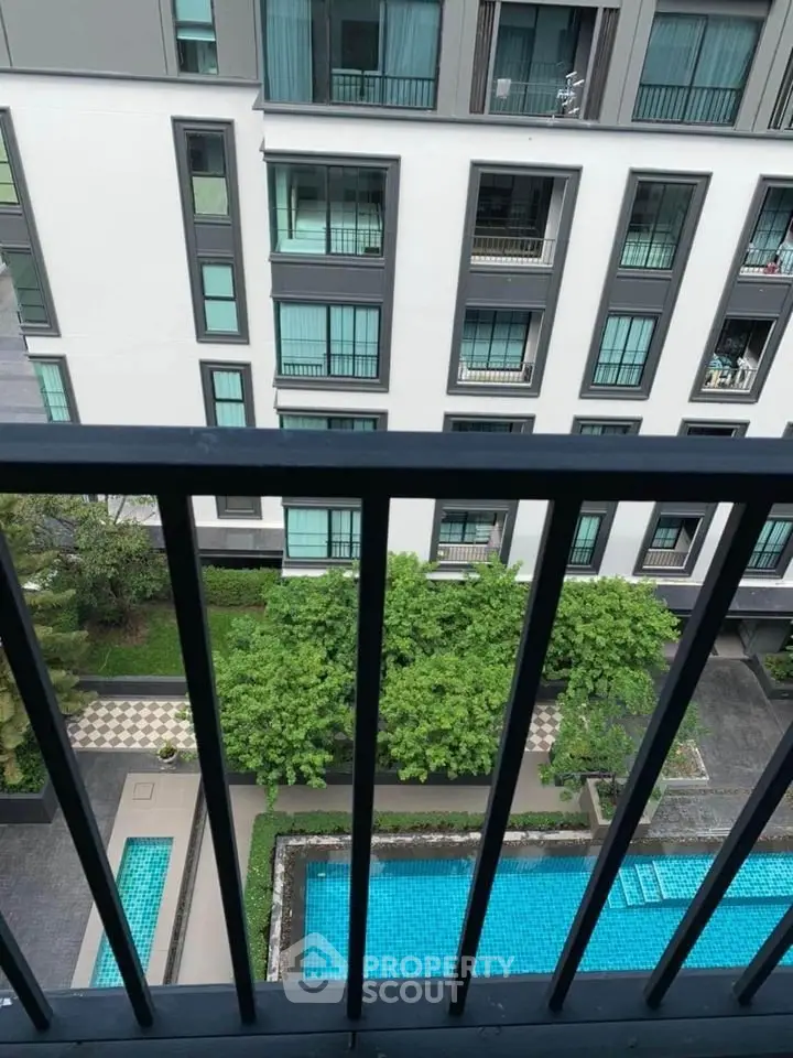 Modern apartment building with pool view from balcony, showcasing urban living and leisure amenities.