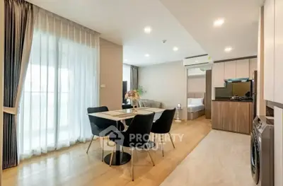Modern open-plan living room with dining area and kitchen in stylish apartment.