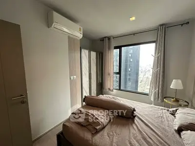 Modern bedroom with city view, featuring cozy bedding and stylish decor.