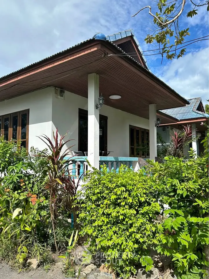 Charming single-story house with lush garden and inviting porch, perfect for serene living.