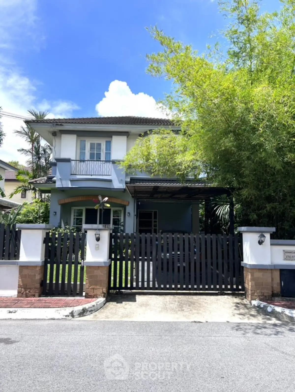 Charming two-story house with lush greenery and gated entrance