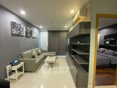 Modern living room with sleek furniture and open view into cozy bedroom.