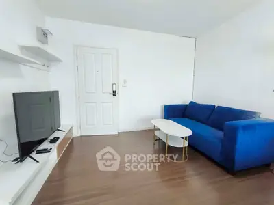 Modern living room with blue sofa and flat-screen TV on wooden floor
