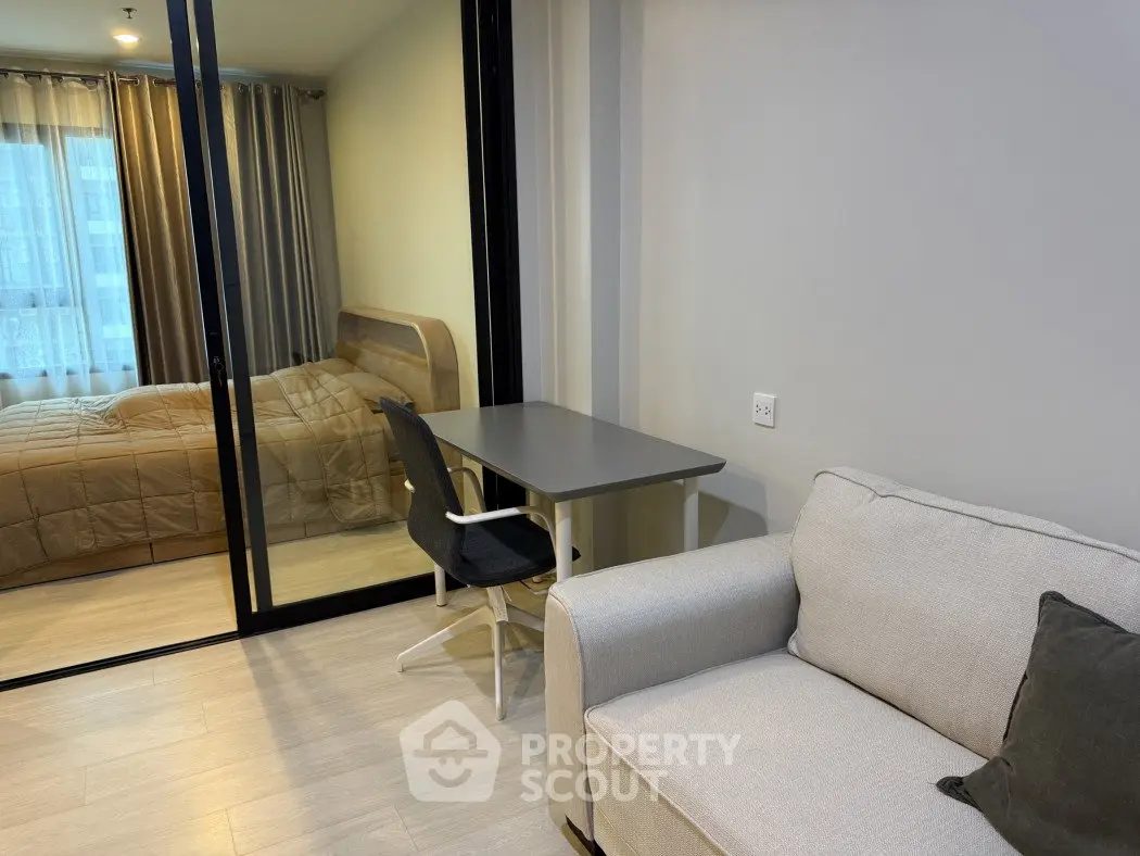 Modern apartment interior with cozy living room and bedroom separated by glass partition.