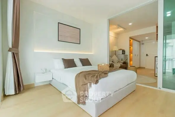 Modern bedroom with cozy decor and sliding glass doors leading to a stylish living area.