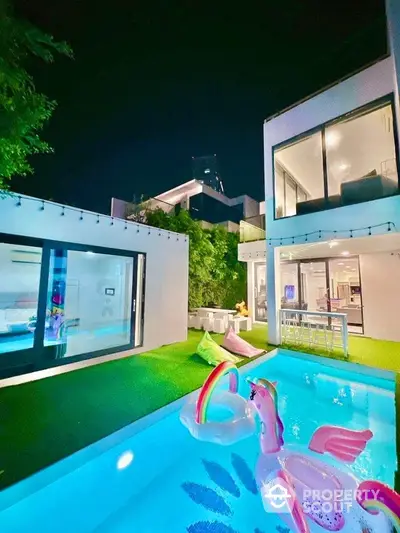 Luxurious modern home with illuminated pool and vibrant unicorn float at night