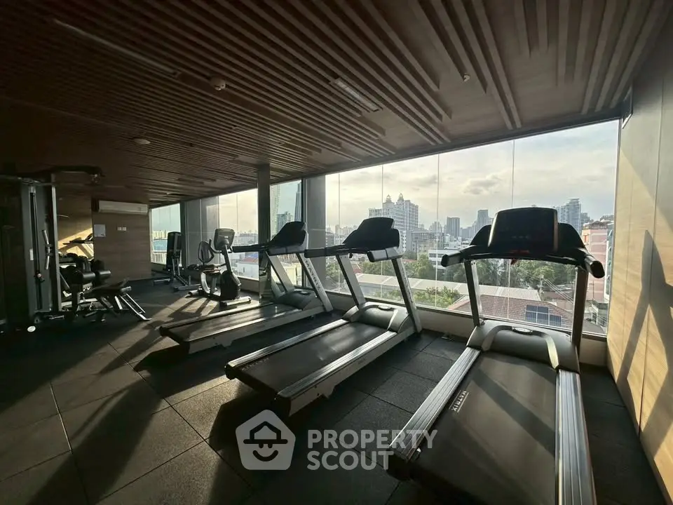 Modern gym with city view and state-of-the-art equipment in luxury high-rise building.