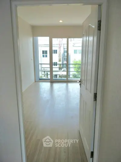 Bright and airy unfurnished living space with gleaming hardwood floors and large balcony doors inviting natural light, perfect for custom interior design.