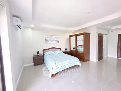 Spacious modern bedroom with elegant wooden furniture and sleek tile flooring.