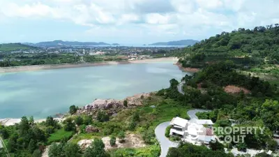 Scenic aerial view of lush landscape with winding road and serene water body.