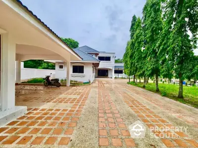 Spacious driveway leading to a luxurious two-story house with lush greenery