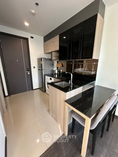 Modern kitchen with sleek cabinetry, built-in appliances, and stylish dining area in a contemporary apartment.