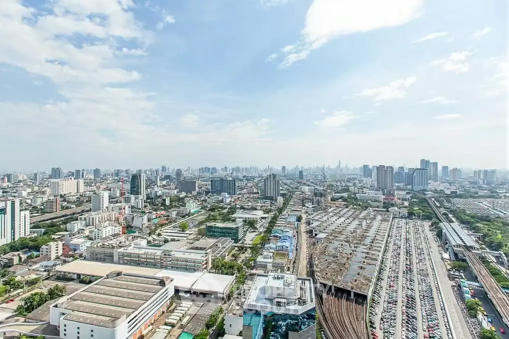 Stunning panoramic city view from high-rise building showcasing urban skyline and railway tracks.