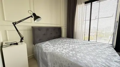 Cozy bedroom with modern decor and large window offering natural light and city views.