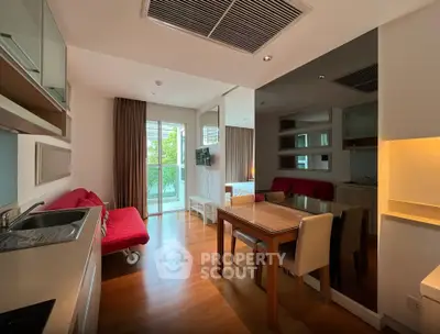 Modern living room with open kitchen and stylish decor, featuring a cozy red sofa and dining area.