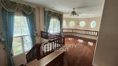 Elegant living room with hardwood floors, large windows, and stylish drapery in a spacious home.