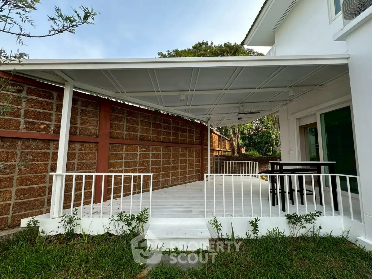 Charming outdoor patio with white pergola and lush greenery, perfect for relaxation and entertaining.