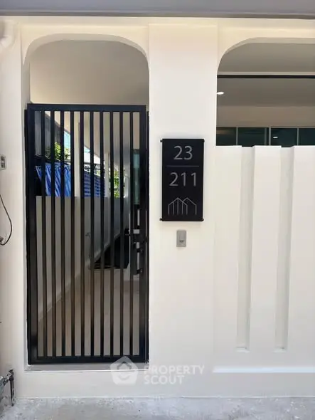 Modern entrance with sleek black gate and house number sign
