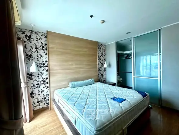 Spacious bedroom with modern decor and large window offering natural light.
