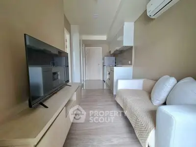 Modern living room with sleek TV, cozy sofa, and compact kitchen in open layout.