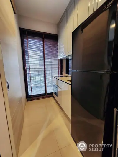 Modern kitchen with sleek black fridge and balcony view