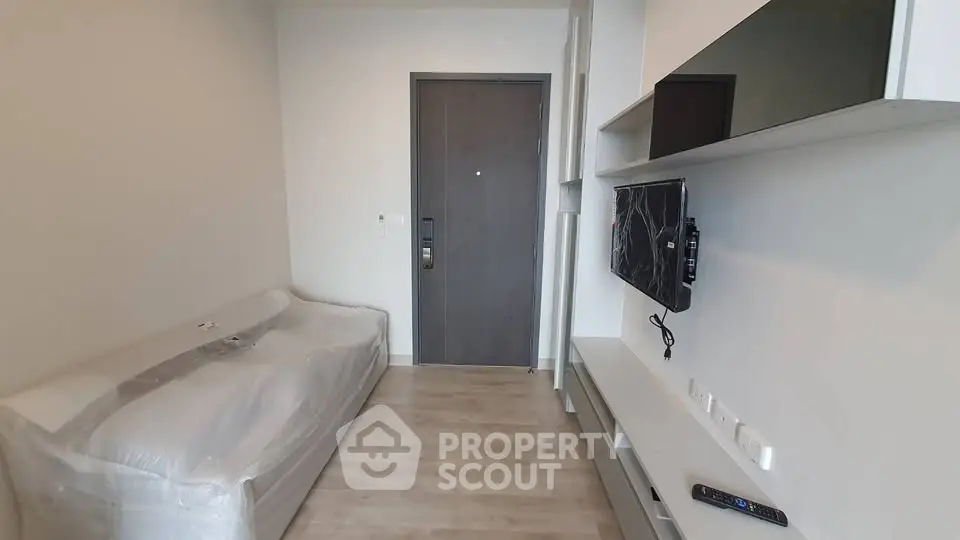Modern living room with sleek furniture and wall-mounted TV in a compact apartment.
