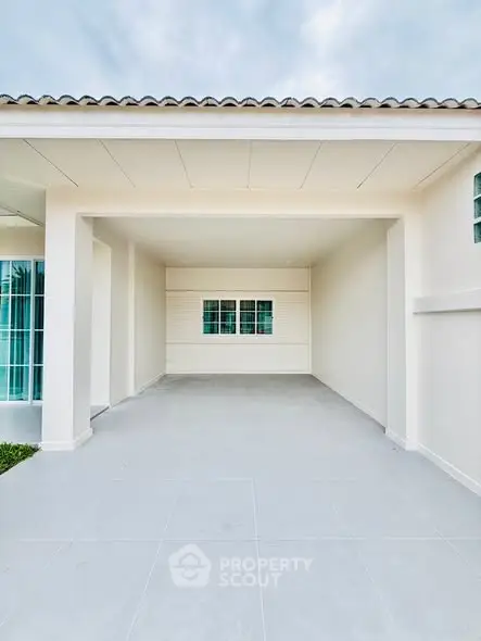 Spacious modern carport with clean lines and tiled flooring in a contemporary home.