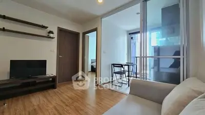 Modern living room with wooden flooring and sliding glass doors to balcony
